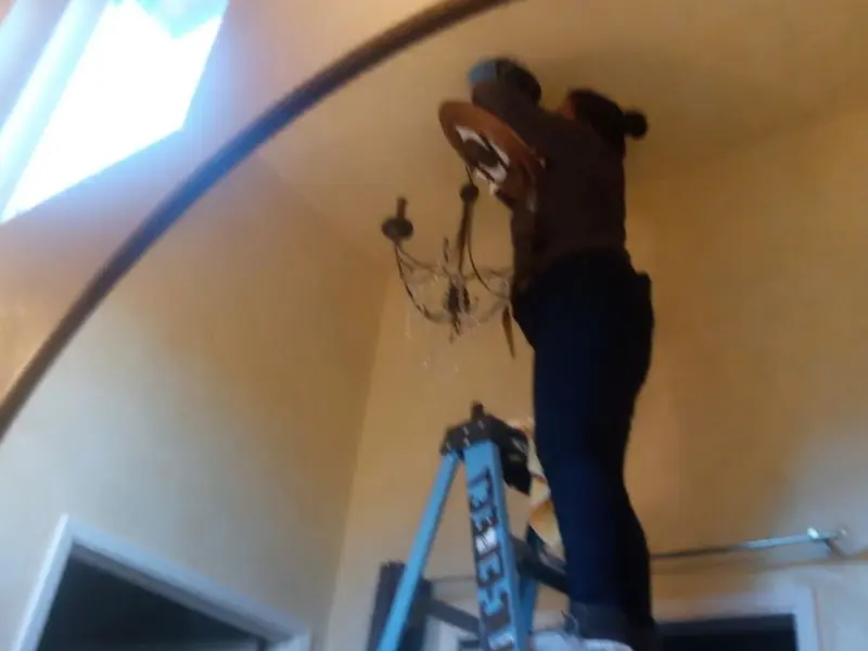 Electrician installing a chandelier in a Westerlo residence